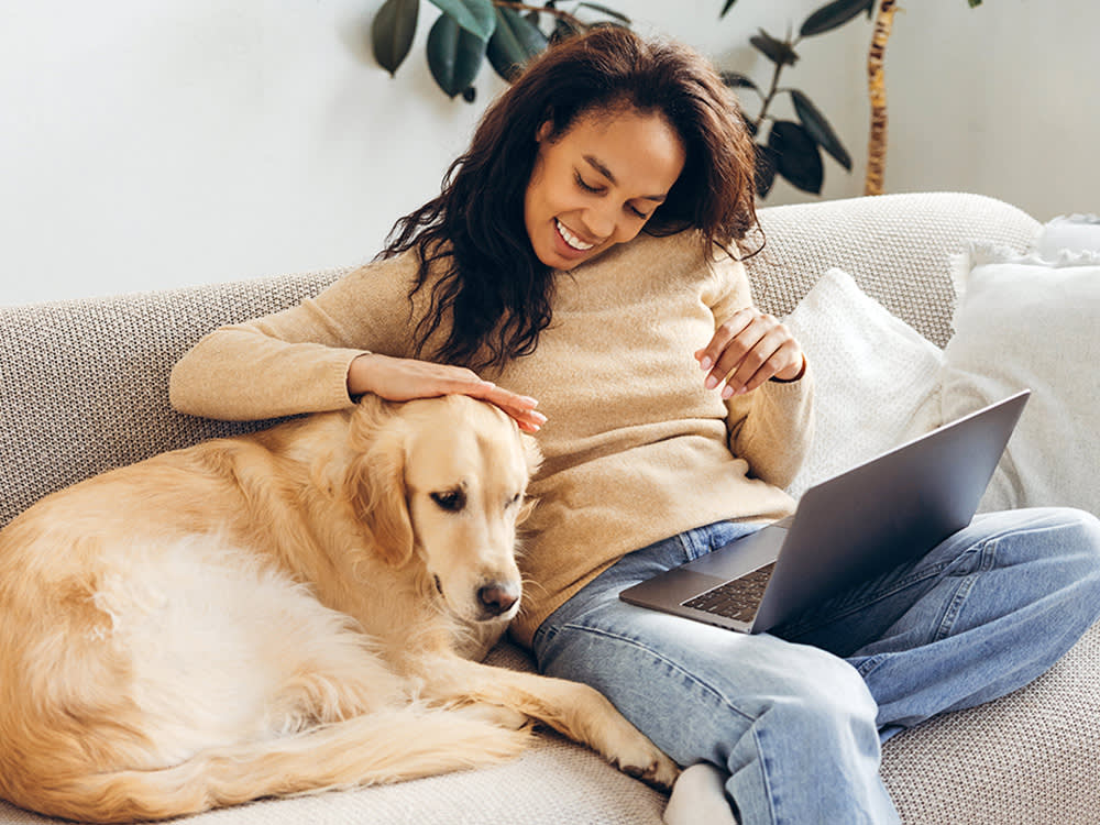 Woman cuddling her dog on the couch at home.