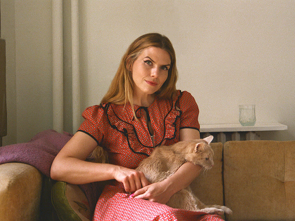 A woman sitting on a couch with her cat.