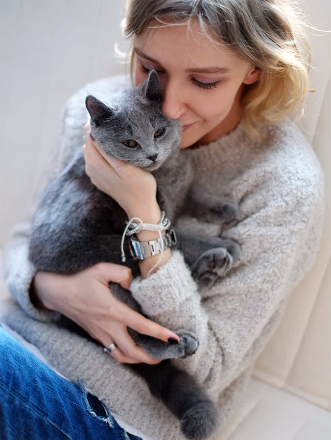 Close up portrait of the young woman holding her cat lovingly.

