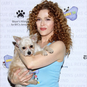 A woman holding a dog and posing for a picture. 