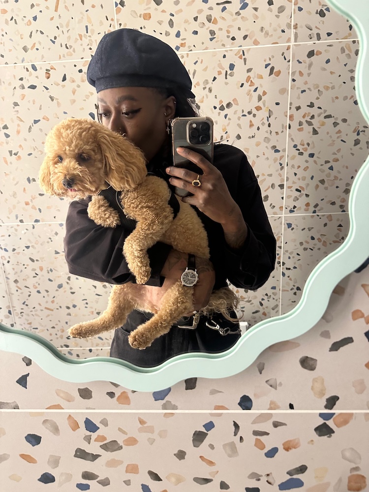 A woman takes a selfie in a mirror with a fluffy dog