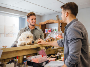 Dog groomer talks at the reception counter with a customer and his dog