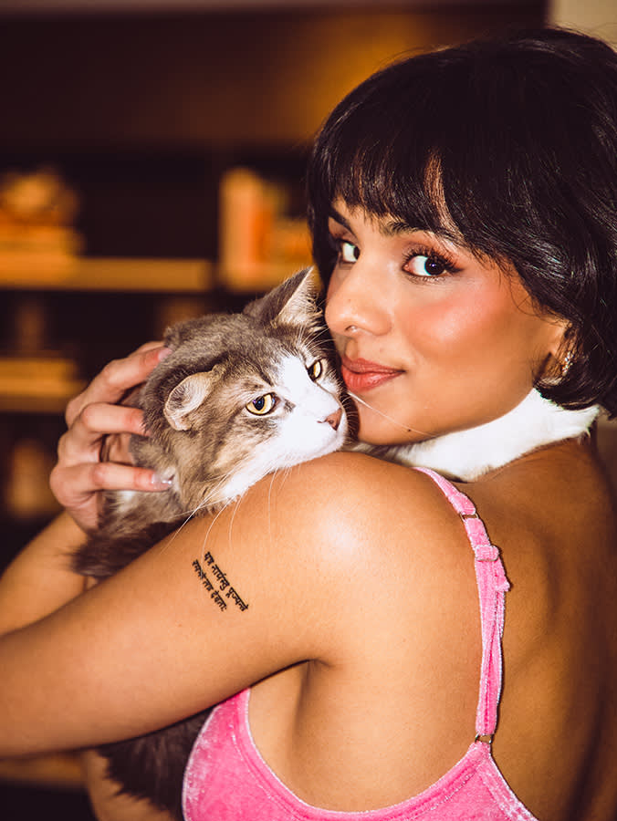 Aparna Brielle snuggles her cat, Oscar Wilde, while looking over her shoulder.