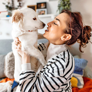 Woman holding her dog in her arms at home.