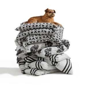 A dog sitting on top of a pile of pillows. 