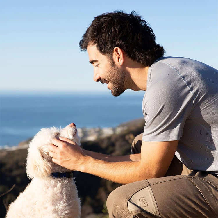 Dave looks down at his dog Stanley, with the sea and rock cliffs in the background.