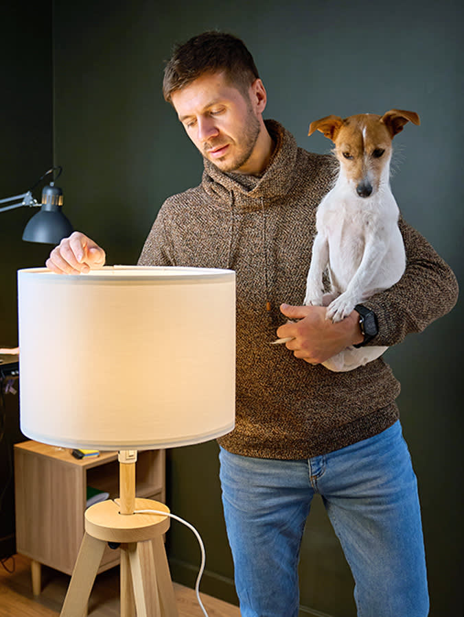 Man turning on a light with his dog at home.