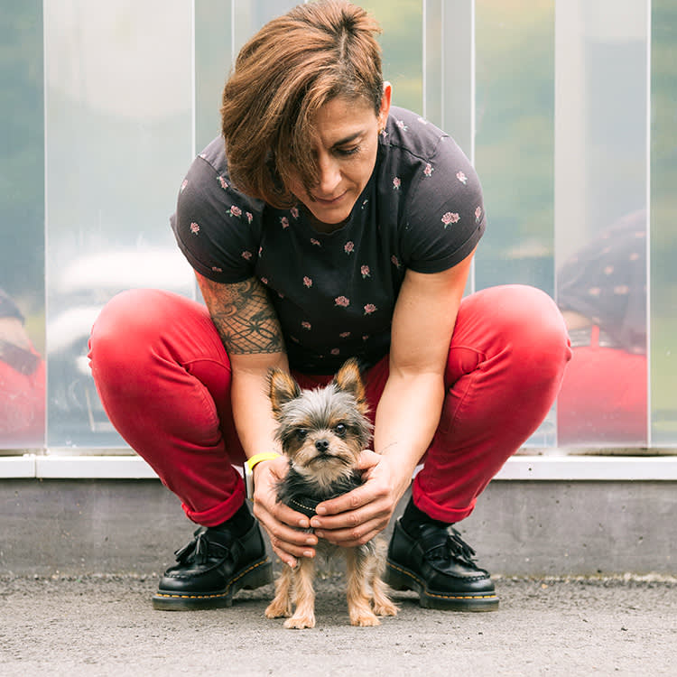 Someone embracing their small dog outside.