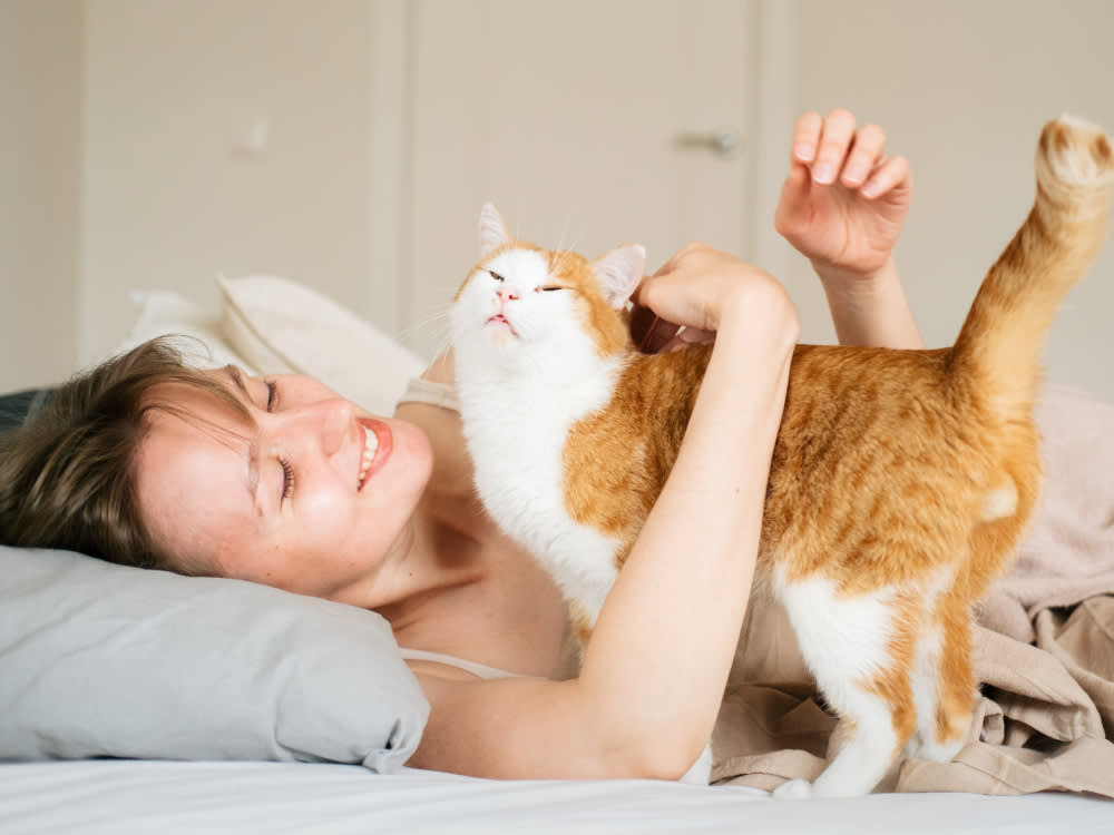 Woman laying on her bed while hugging her cat