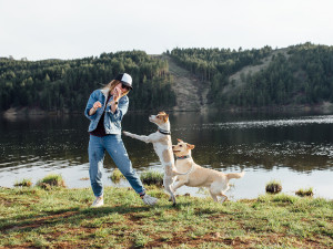 A woman with two playful dogs running after her. 