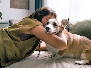 Woman trying to cuddle her dog at home.