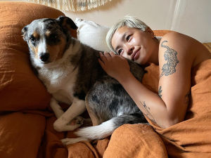 Jess Tran laying in a bed looking lovingly at her dog.