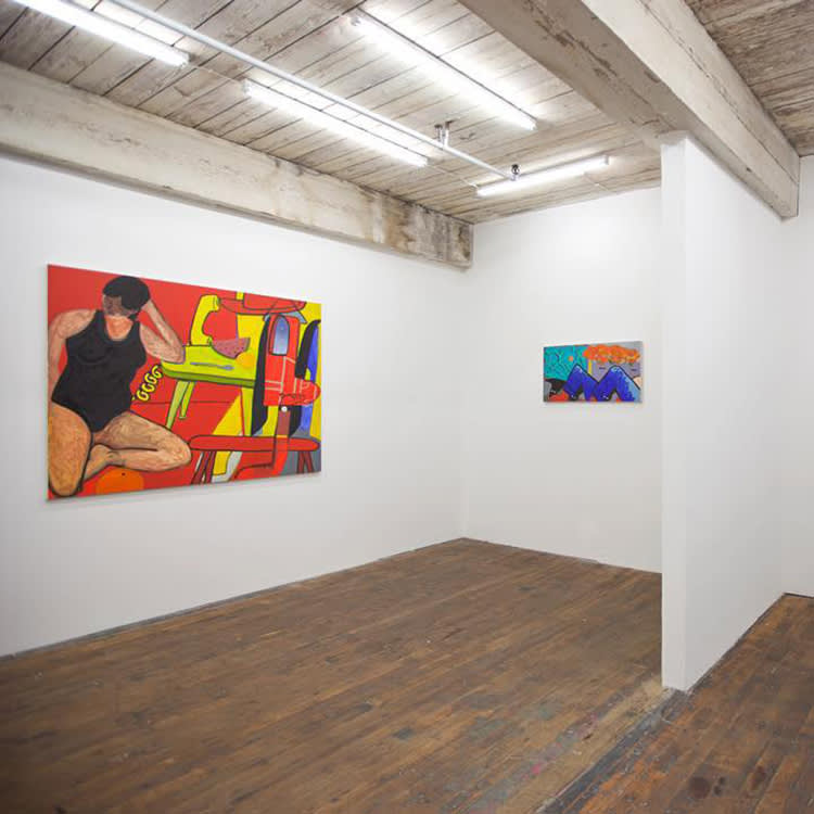 A photo of two paintings hanging on the gallery walls
