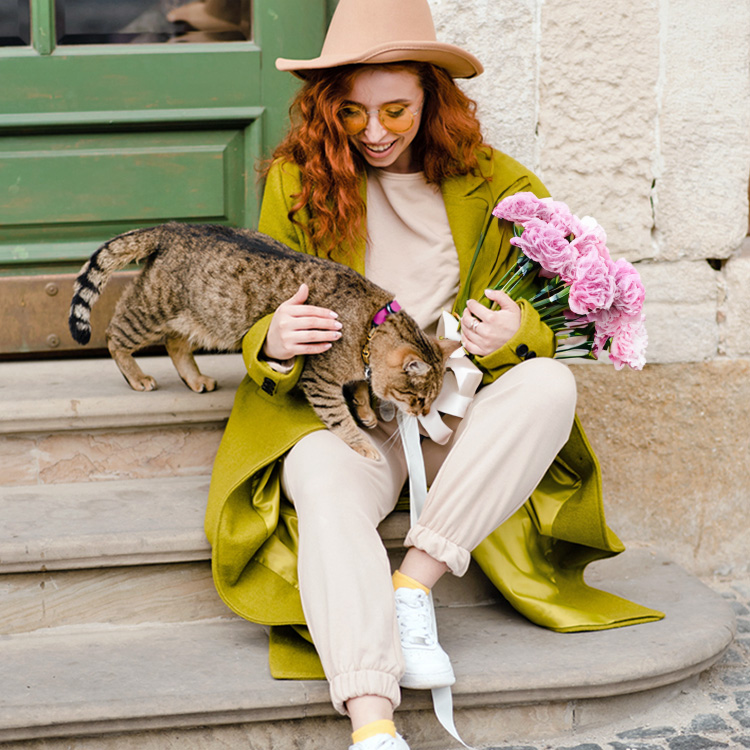 Woman outside with her cat and a bouquet of carnations.