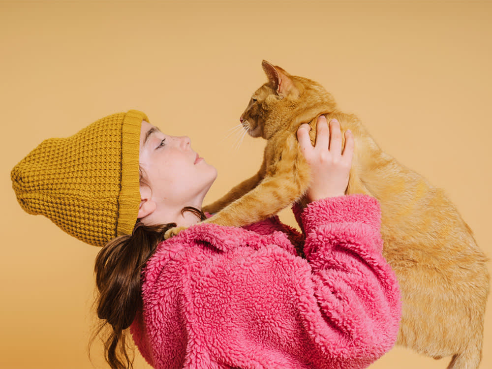 Woman playing with her orange cat.