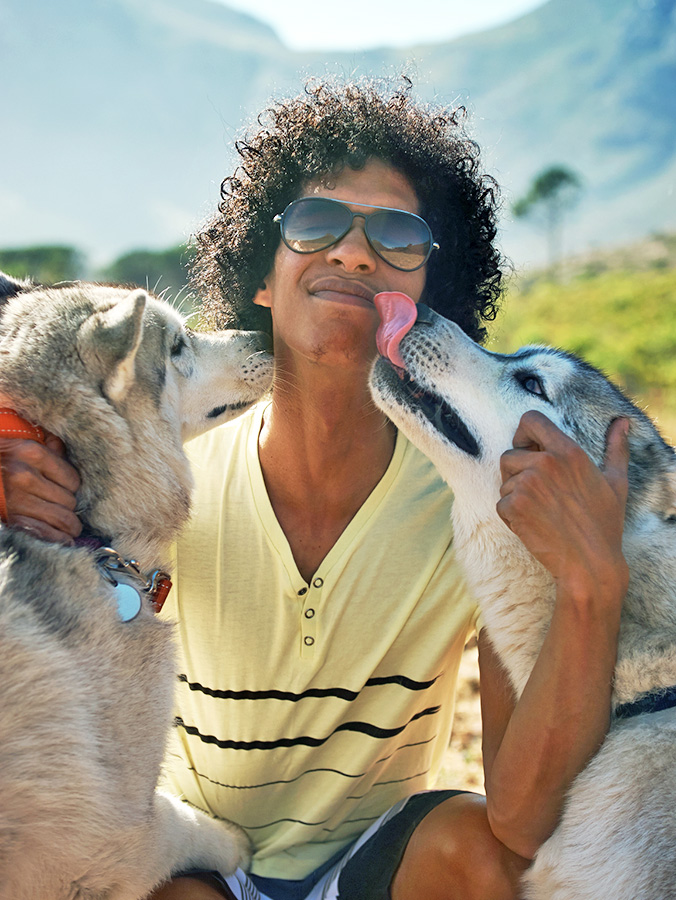 Man petting his two Husky dogs outside.