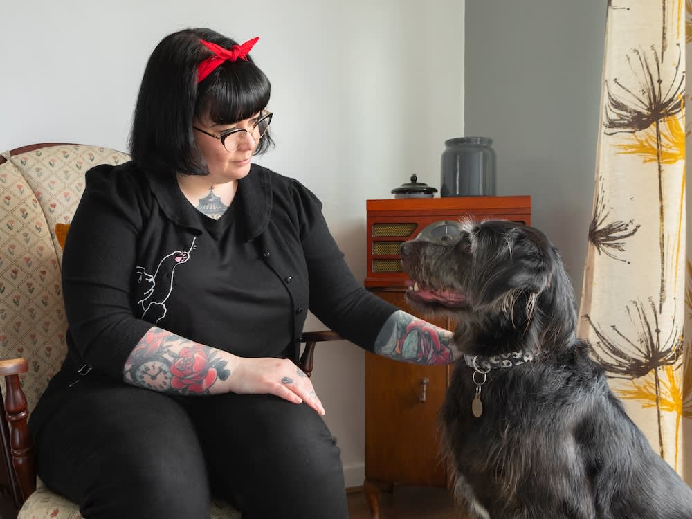 woman with tattoos strokes big grey dog