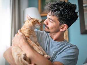 Man holding his cat at home.