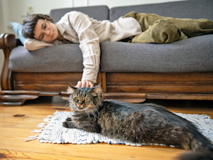 Woman petting her cat at home.