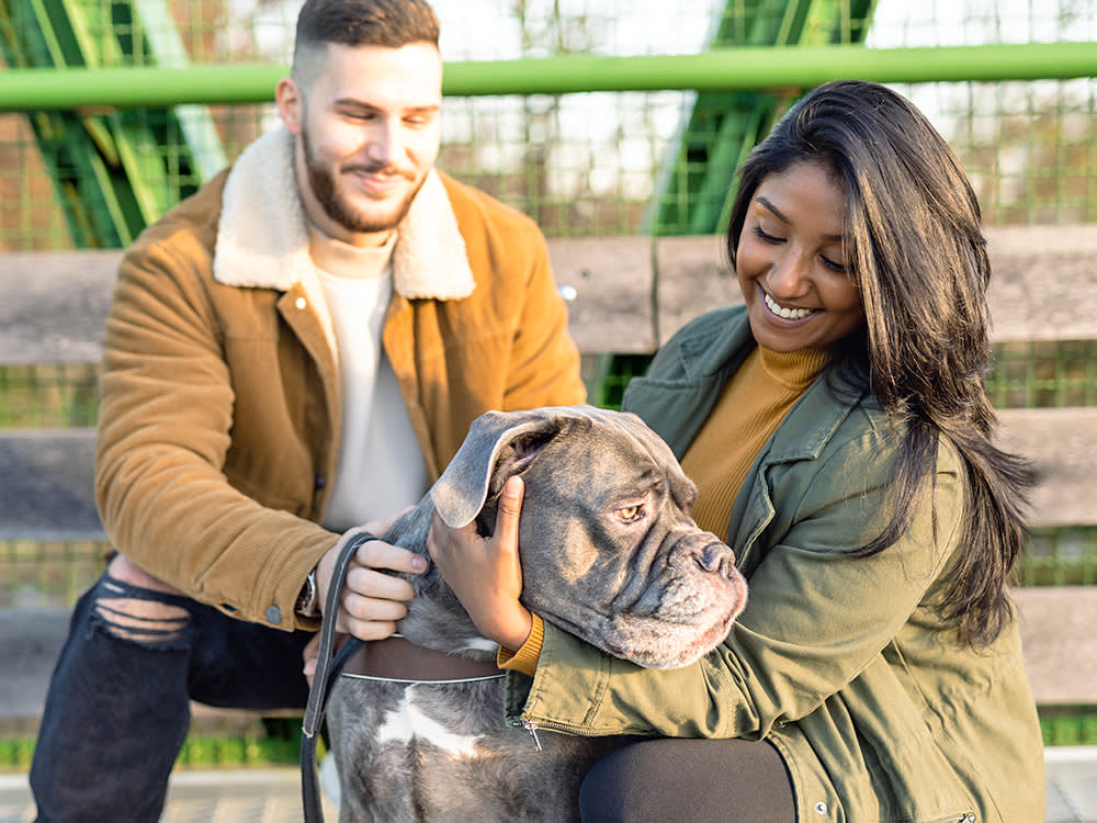 Man and woman petting a dog outside.