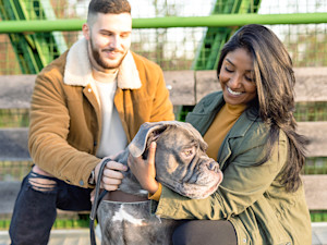 Man and woman petting a dog outside.