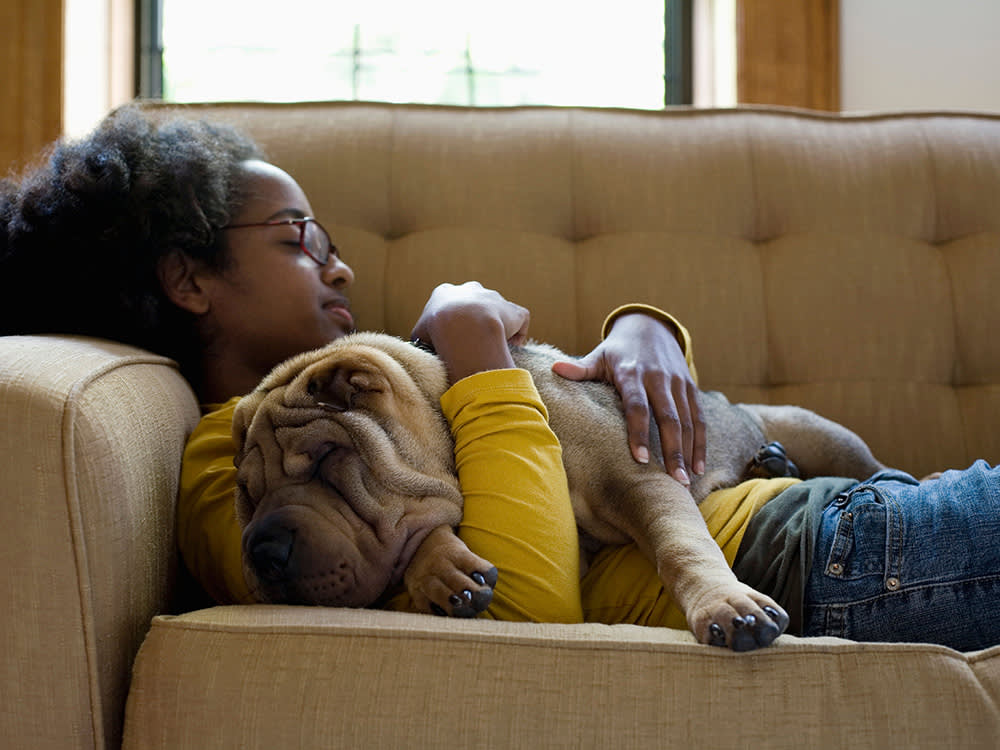 A young woman and her Shar-Pei napping on a couch.