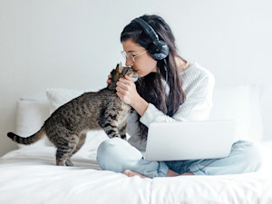 Woman snuggling her striped gray cat at home.