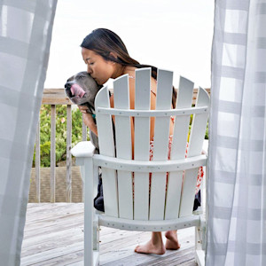 Woman kisses her pitbull dog outside.