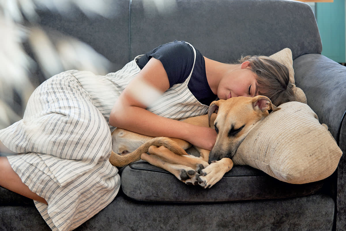 woman cuddles her dog on the couch