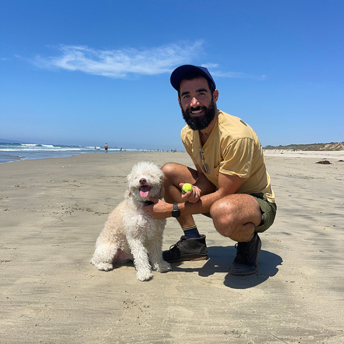 Dave Coast with his small white dog on a beach