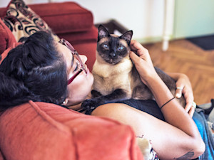 Woman holding cat at home.