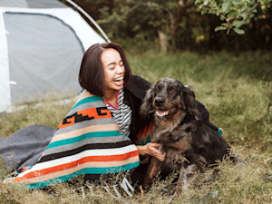 Woman camping with her dog outside.
