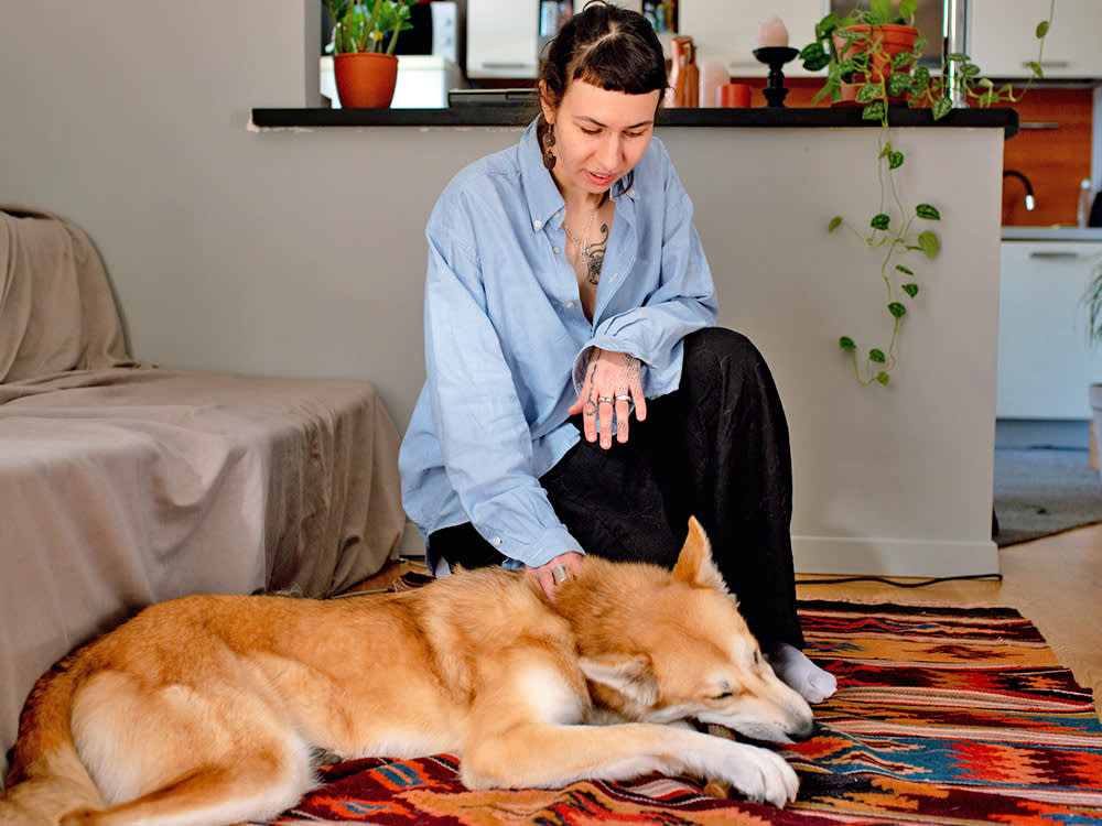 Woman rubbing her dog's back at home.
