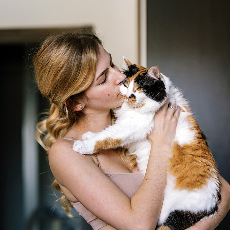 Woman holding cat at home.
