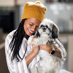 Woman snuggling her dog outside.