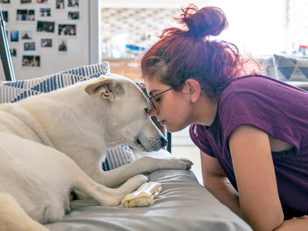 Woman and her dog snuggling at home.