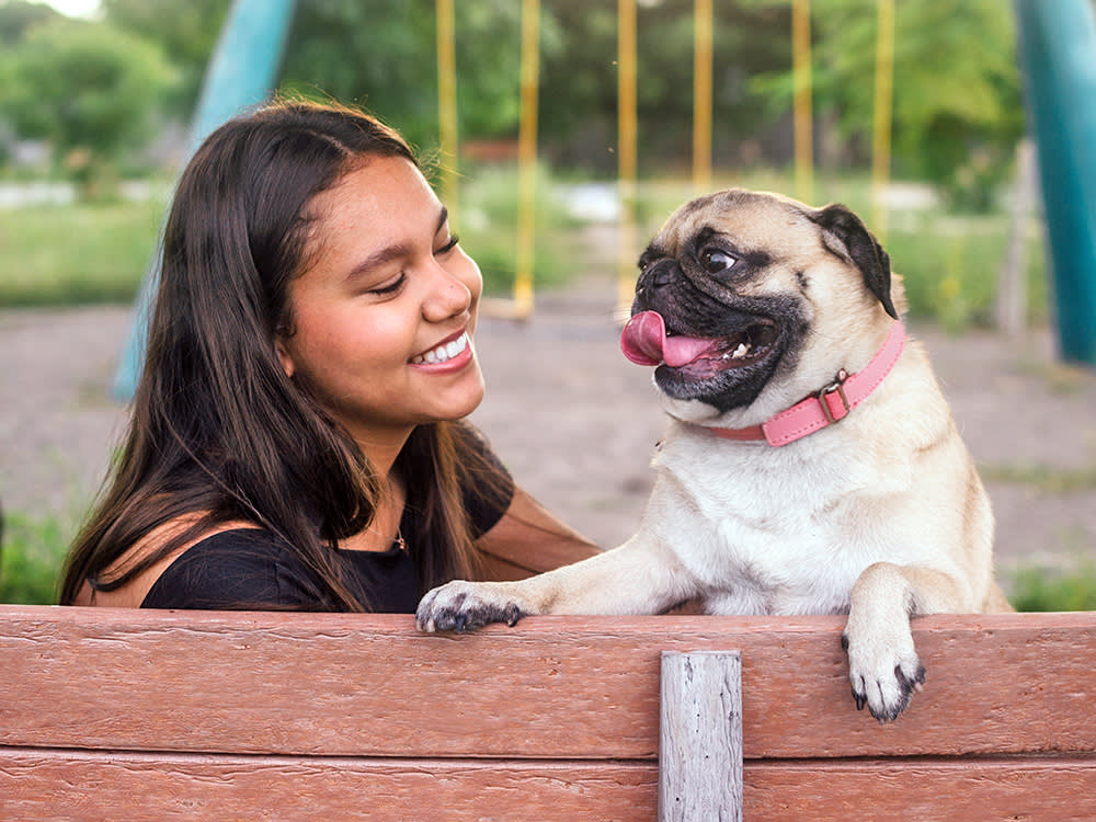 Woman with her pet Pug outside at the park.