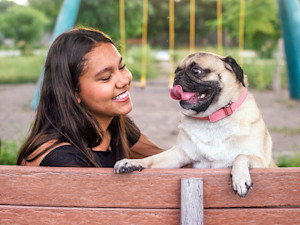 Woman with her pet Pug outside at the park.