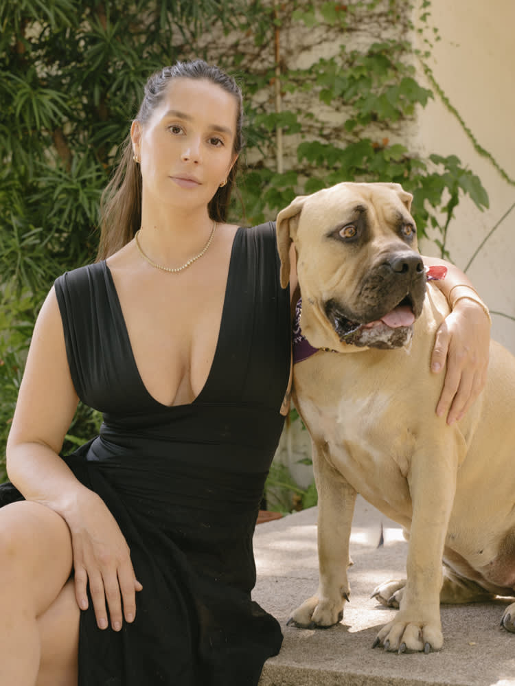  Pia Baroncini wearing a black dress posing for a picture with her arm around her dog. 