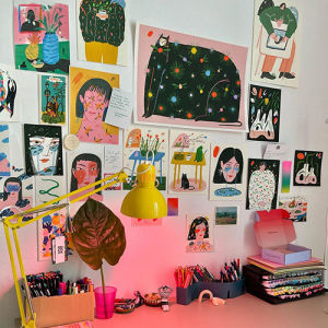 illustrated drawings above Livia Fălcaru's work space, a desk with a yellow lamp 