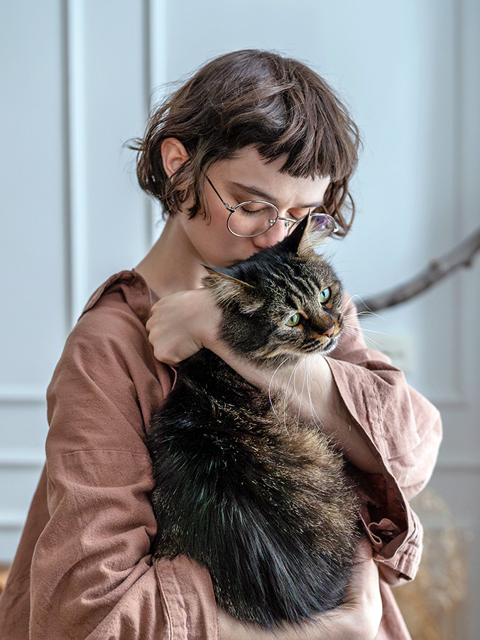 Woman holding her cat in her arms at home.