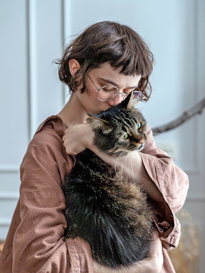 Woman holding her cat in her arms at home.