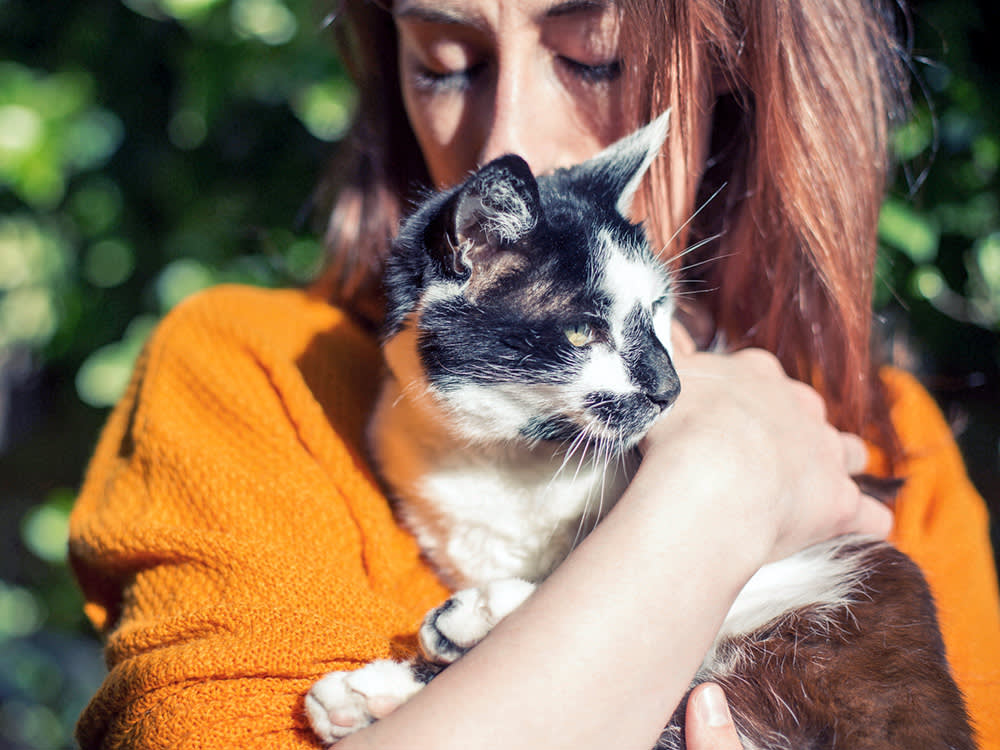 Woman snuggling her cat outside.