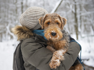 A woman holding a dog outside in the snow 
