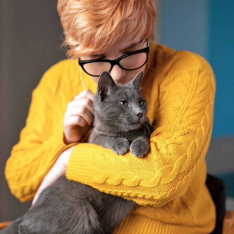 Woman holding her cat in her arms.