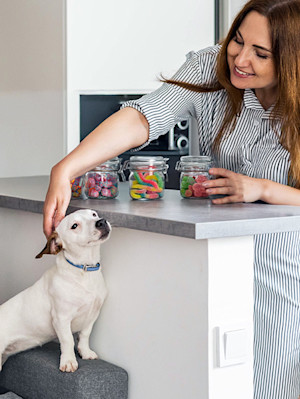 Woman organizing her jars of candy while dog watches at home.