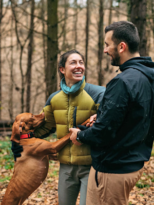 man and woman with dog in the woods