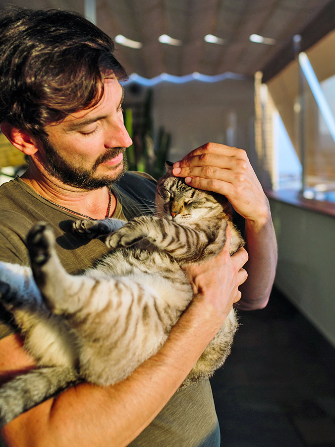Man cuddling cat in his arms.