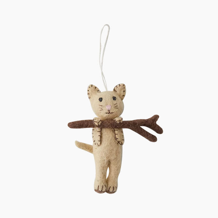 ornament of felted cat in beige hanging onto a branch