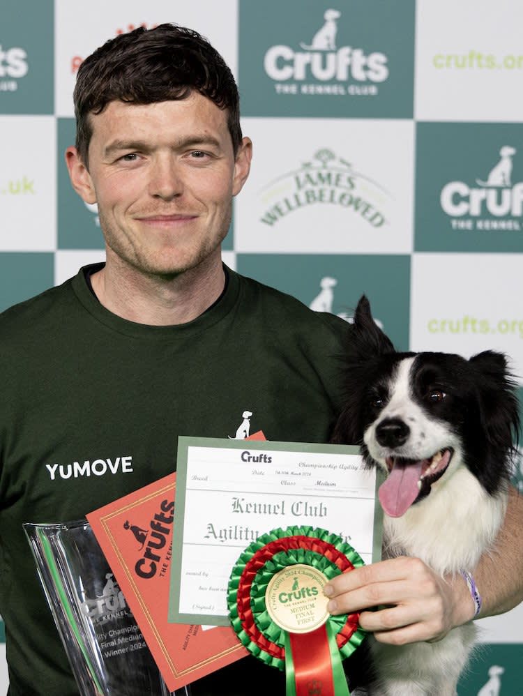 man with brown hair hugging a sheepdog and holding a rosette at crufts